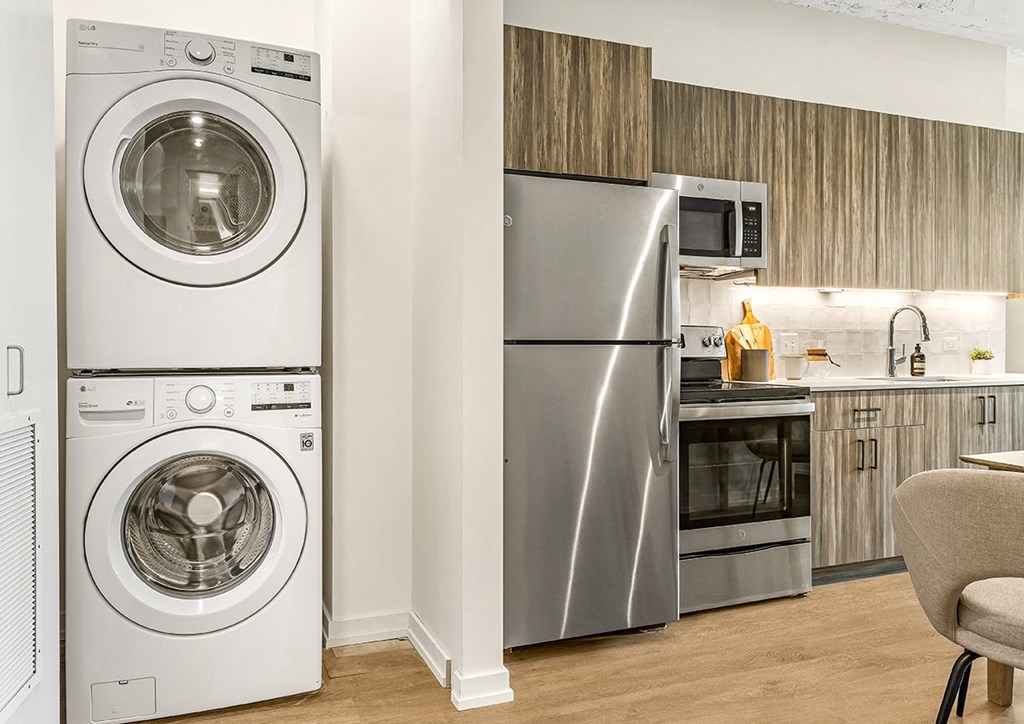 a kitchen with a washing machine and a stainless steel refrigerator