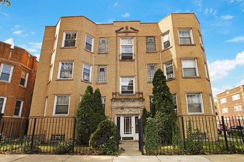 A large brick building with a black iron fence in front.