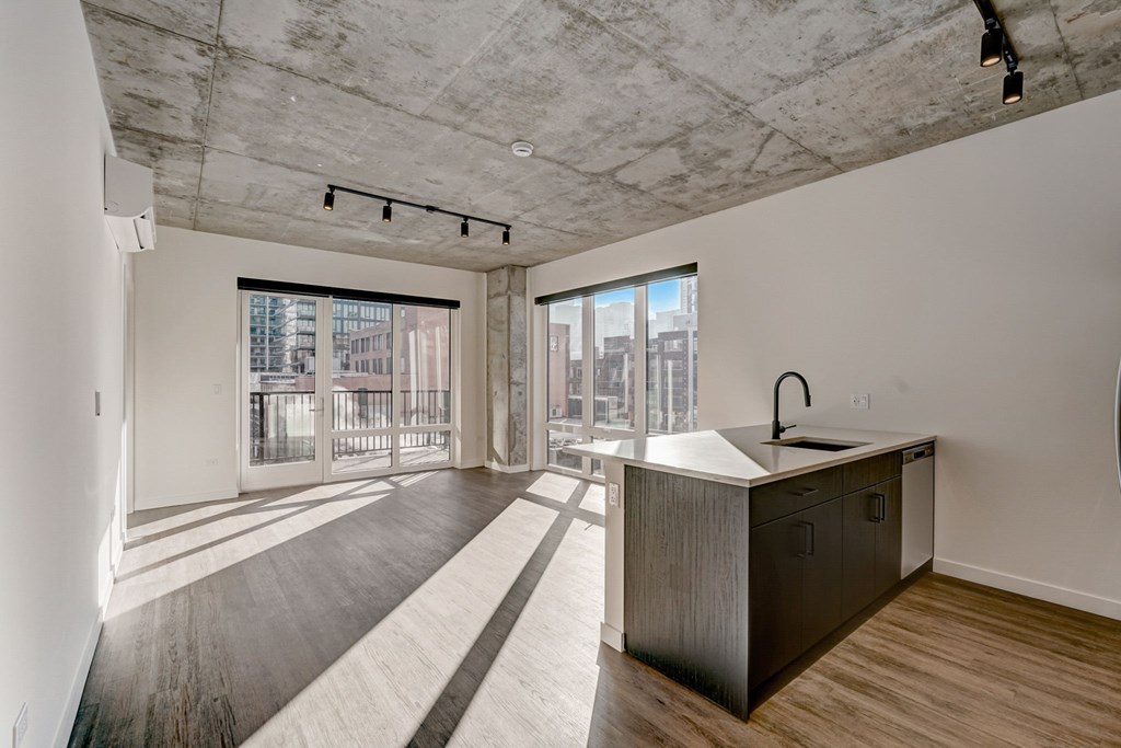 A kitchen with a concrete ceiling and a sink.