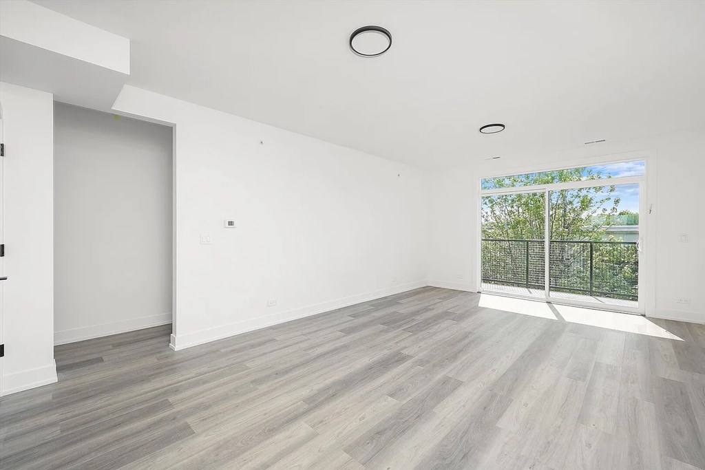 A spacious room with a large window and a sliding glass door.