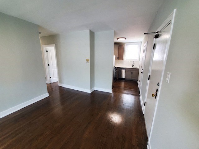 an empty living room and kitchen with wood floors