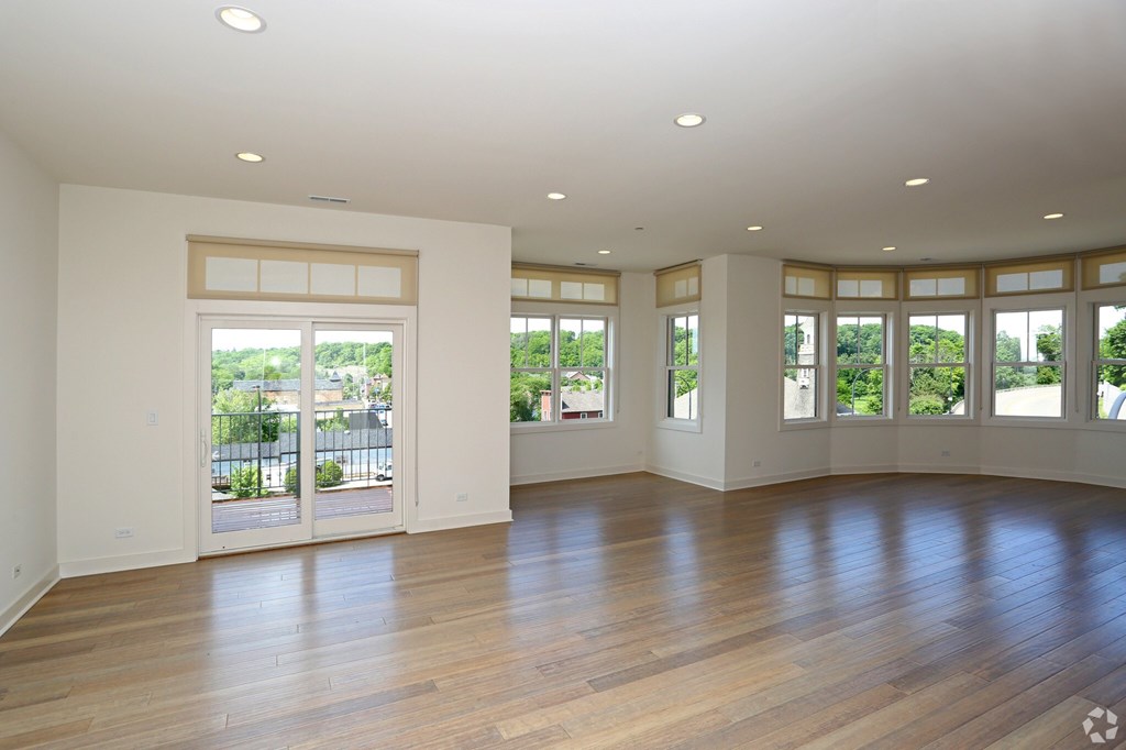 A spacious room with wooden floors and large windows.