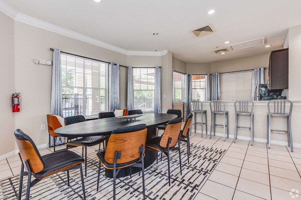 A dining room with a black table and chairs.