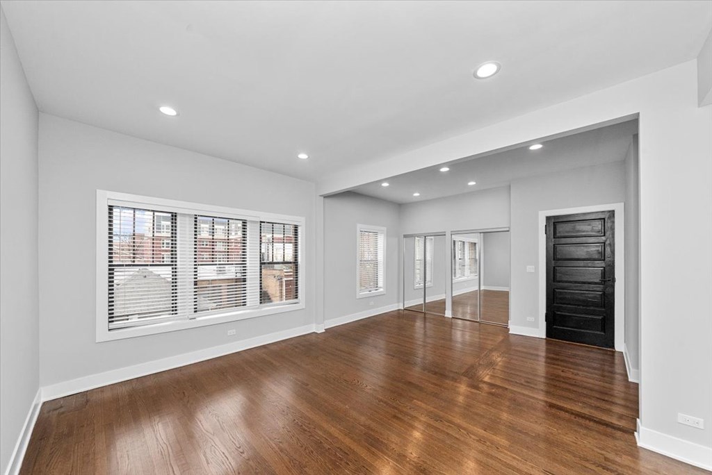 A spacious room with wooden floors and white walls.