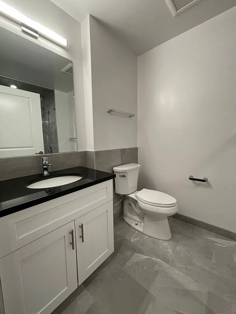 A bathroom with a toilet, sink, and mirror.