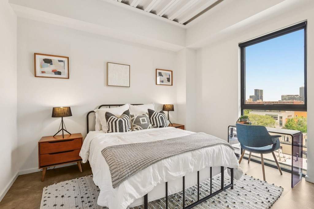 A bedroom with a large bed and a chair by the window.