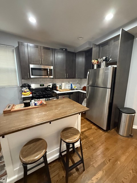 A kitchen with a wooden bar and stools.