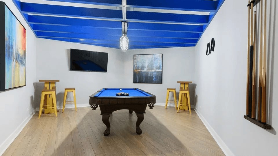 A pool table is in the middle of a room with a blue ceiling.