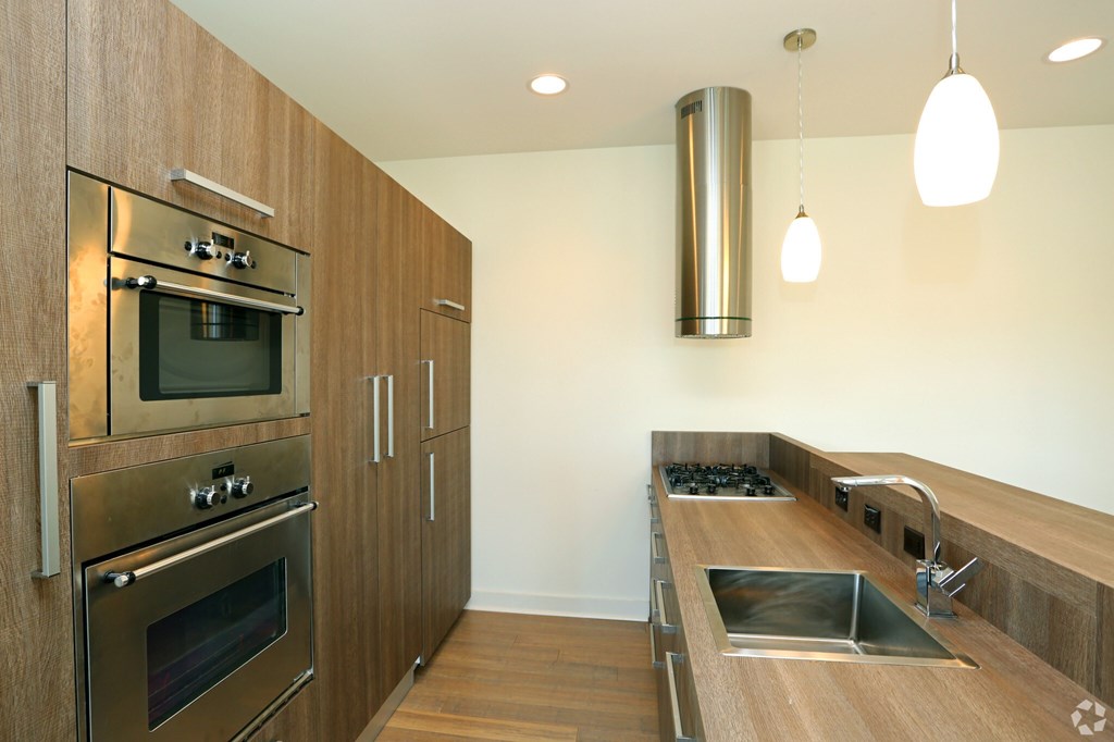 A modern kitchen with a stainless steel oven and wooden cabinets.