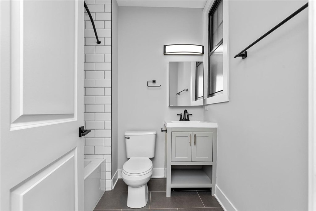 A white bathroom with a toilet, sink, and mirror.