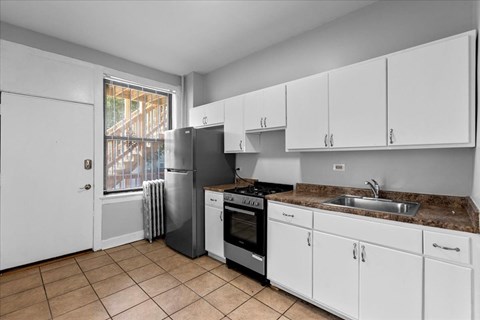 A kitchen with white cabinets and a brown countertop.
