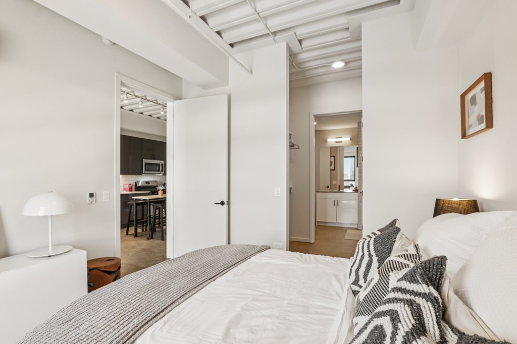 A bedroom with a bed, a lamp, and a picture on the wall.