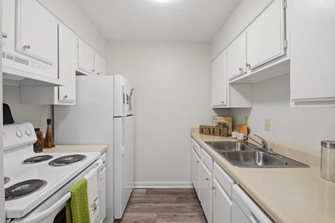 A kitchen with white cabinets and a white stove.