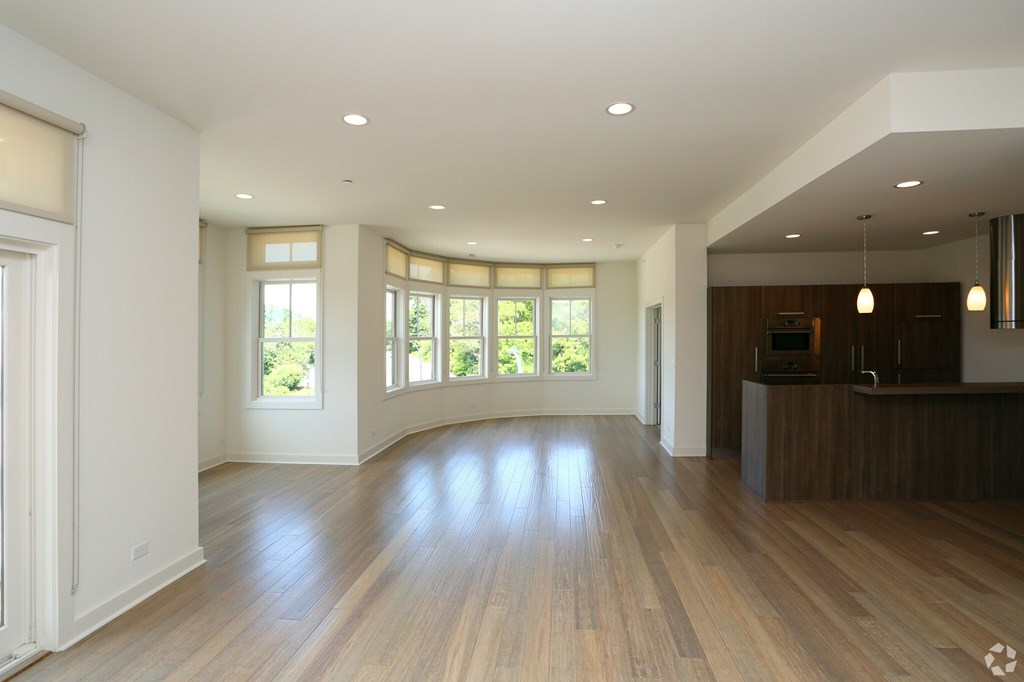 A spacious living room with wooden floors and large windows.