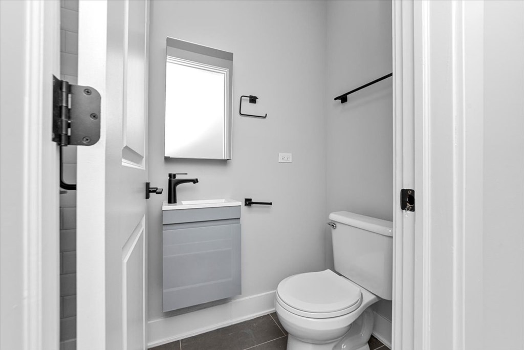 A white bathroom with a toilet, sink, and mirror.