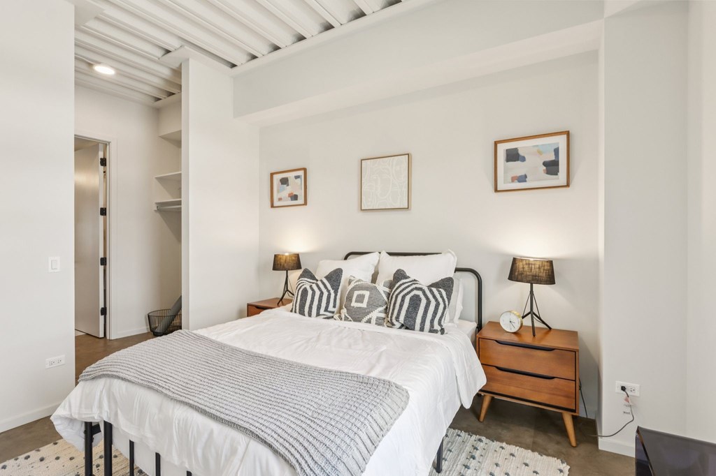 A bedroom with a bed, nightstand, and two pictures on the wall.