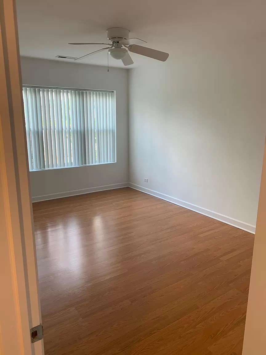 an empty room with wooden floors and a ceiling fan