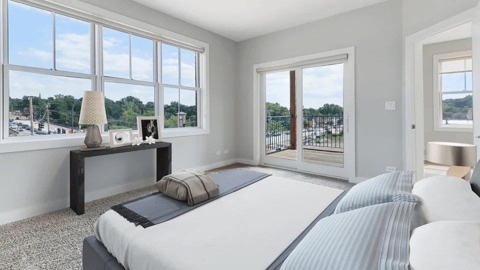 A bedroom with a large bed and a view of the outside through the windows.