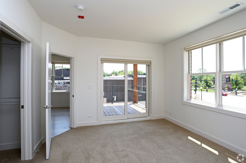 A room with a carpet floor, a sliding glass door, and a window.