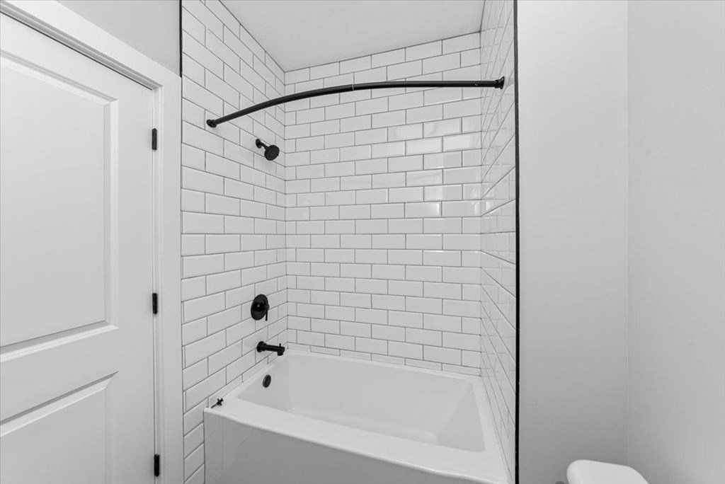 A white bathroom with a white tub and a white door.