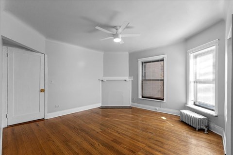 A room with a ceiling fan and a window with blinds.
