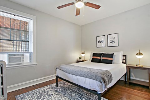 A bedroom with a bed, two lamps, and a ceiling fan.