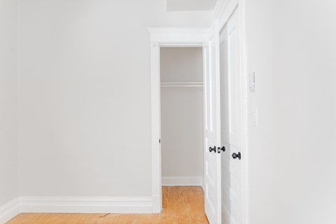 A white door with a black handle is open to a hallway.