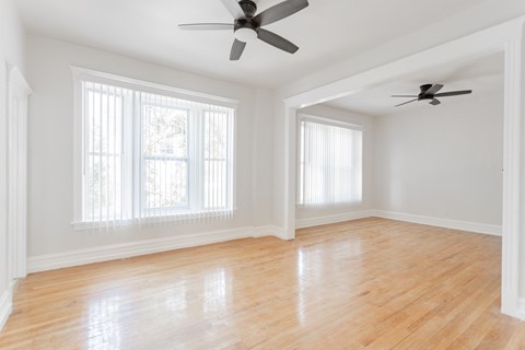 A room with wooden floors and two ceiling fans.