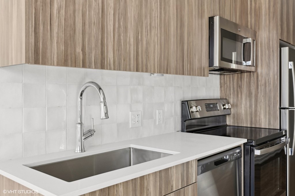 A modern kitchen with a stainless steel sink and oven.