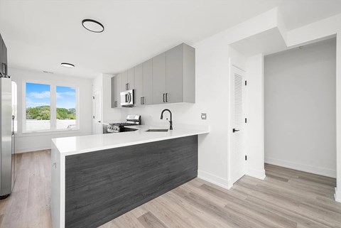 A modern kitchen with a refrigerator, microwave, and oven.