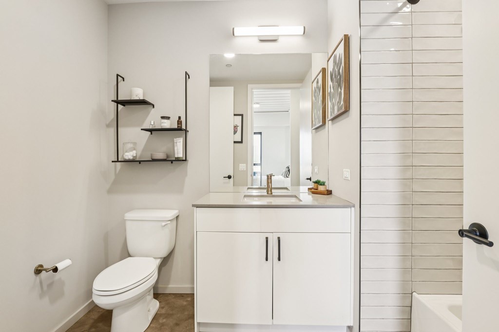 A white bathroom with a toilet, sink, and shelves.