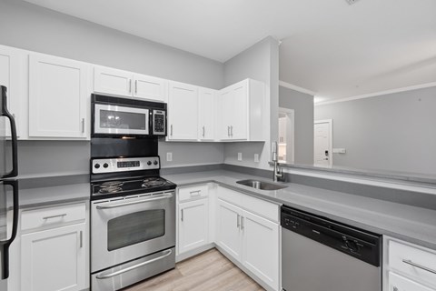 A modern kitchen with white cabinets and stainless steel appliances.