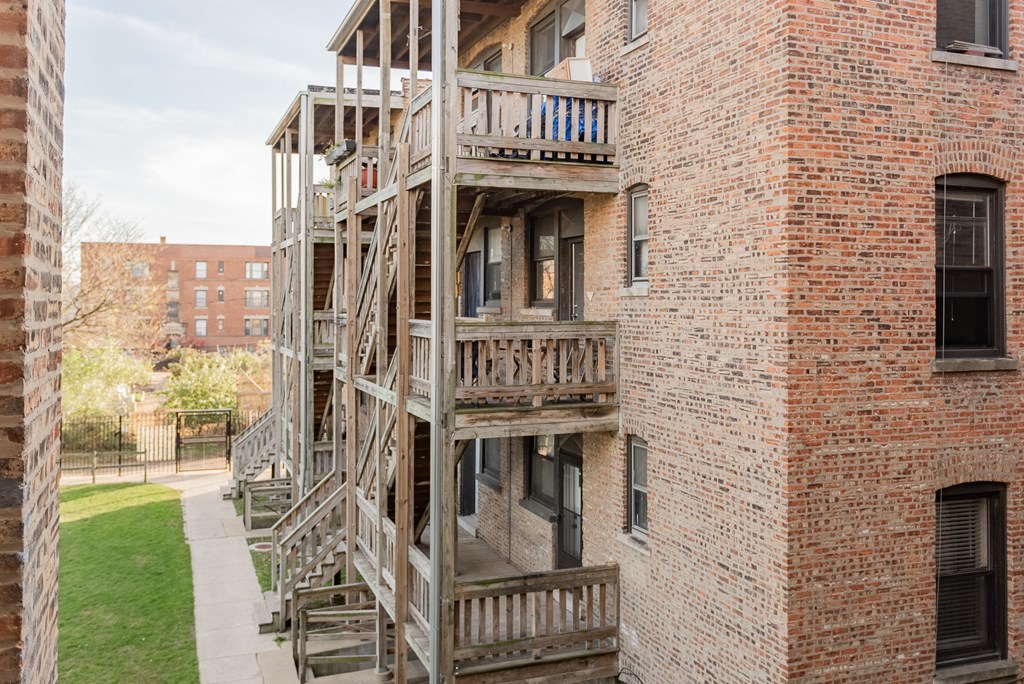 the exterior of a brick apartment building with wooden stairs