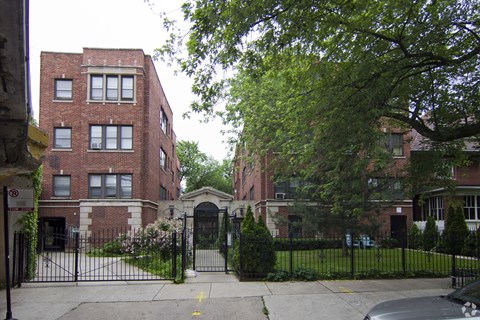 A black gate blocks the entrance to a brick building.