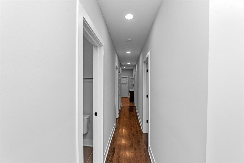 A long hallway with white walls and wood floors.