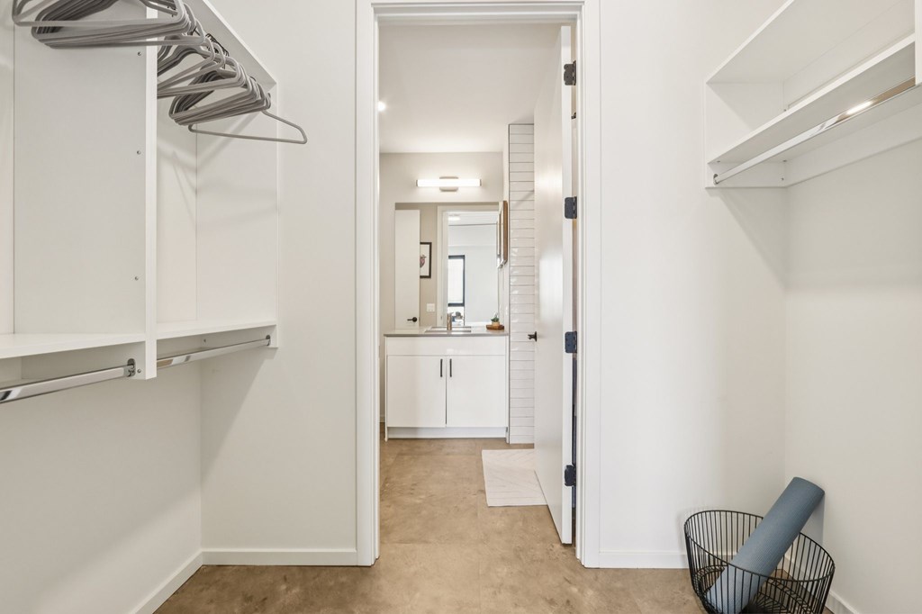 A small white room with a mirror and a black wire basket.