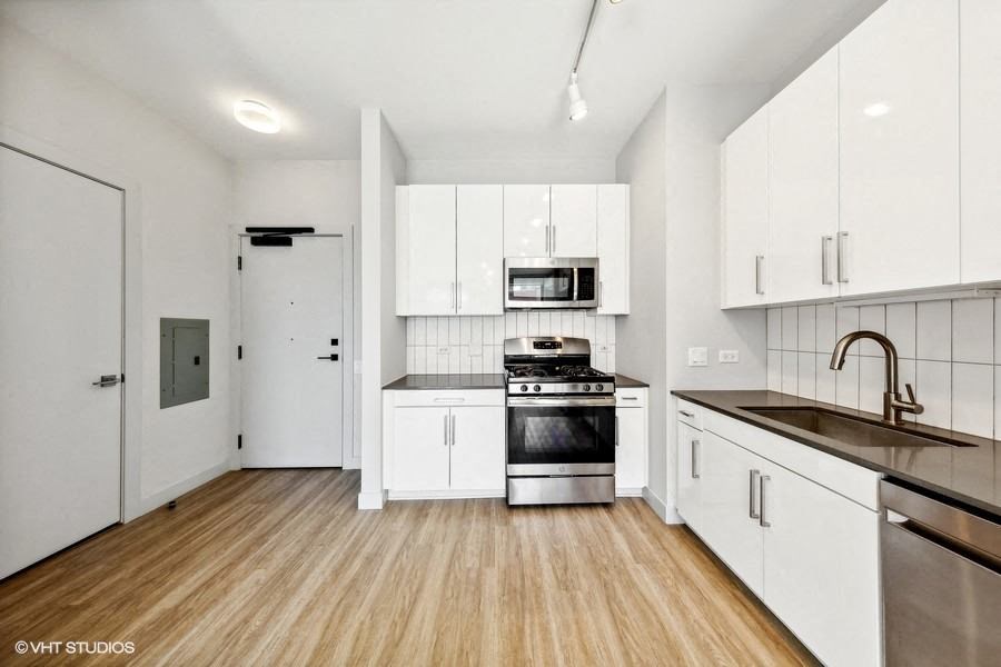 an empty kitchen with white cabinets and stainless steel appliances