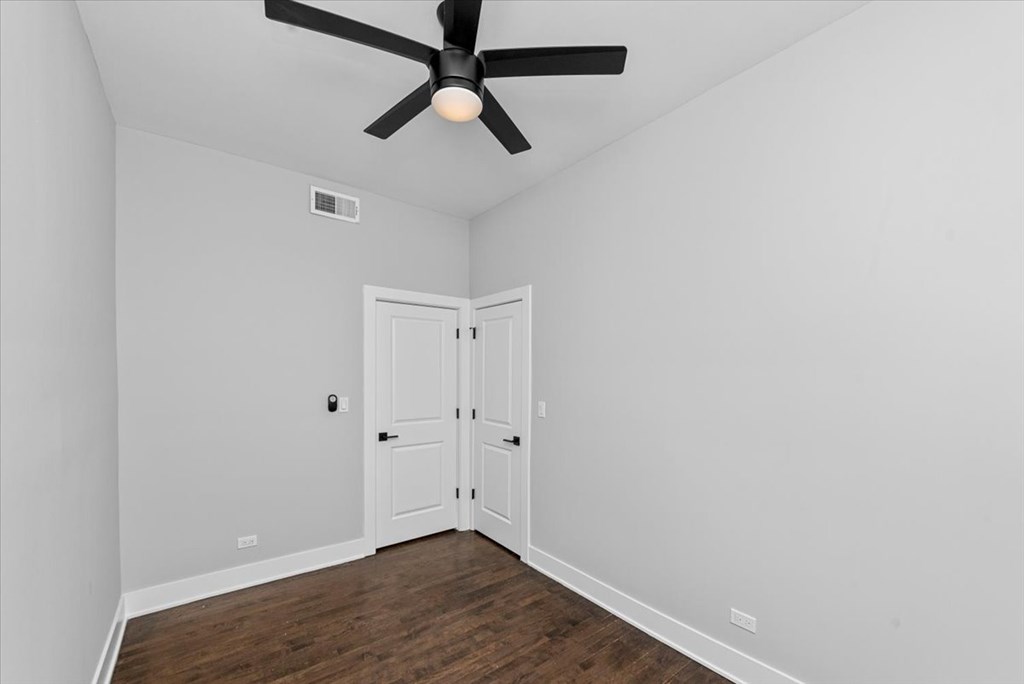 A room with a ceiling fan and a door.