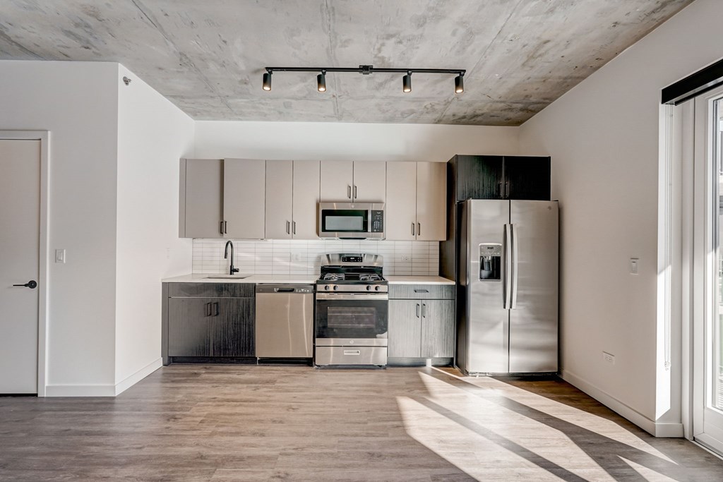 A modern kitchen with a stainless steel refrigerator and a microwave above the stove.