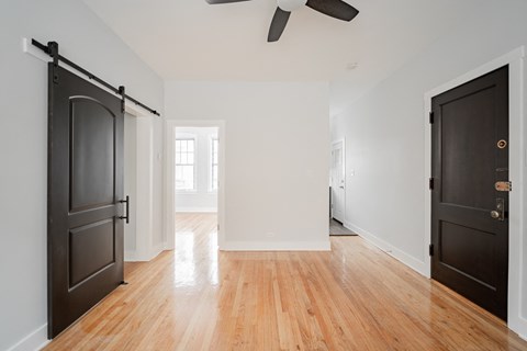 a living room with black doors and a wooden floor and a ceiling fan