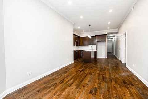 a living room and kitchen with wood floors and white walls