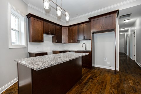 A kitchen with dark wood cabinets and a granite countertop.