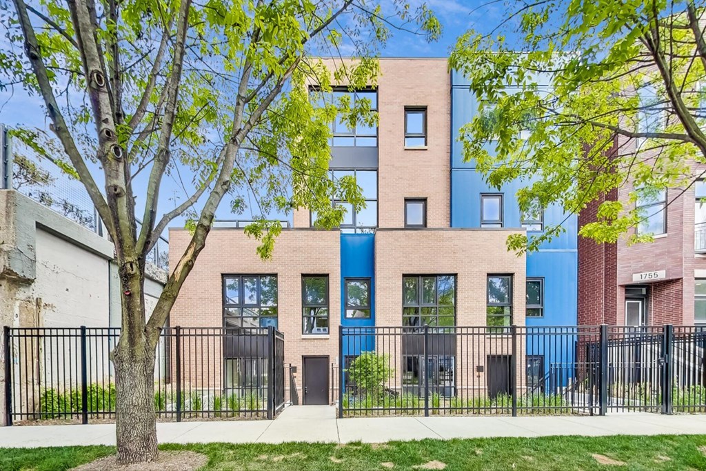 a brick building with blue doors and a tree in front of it