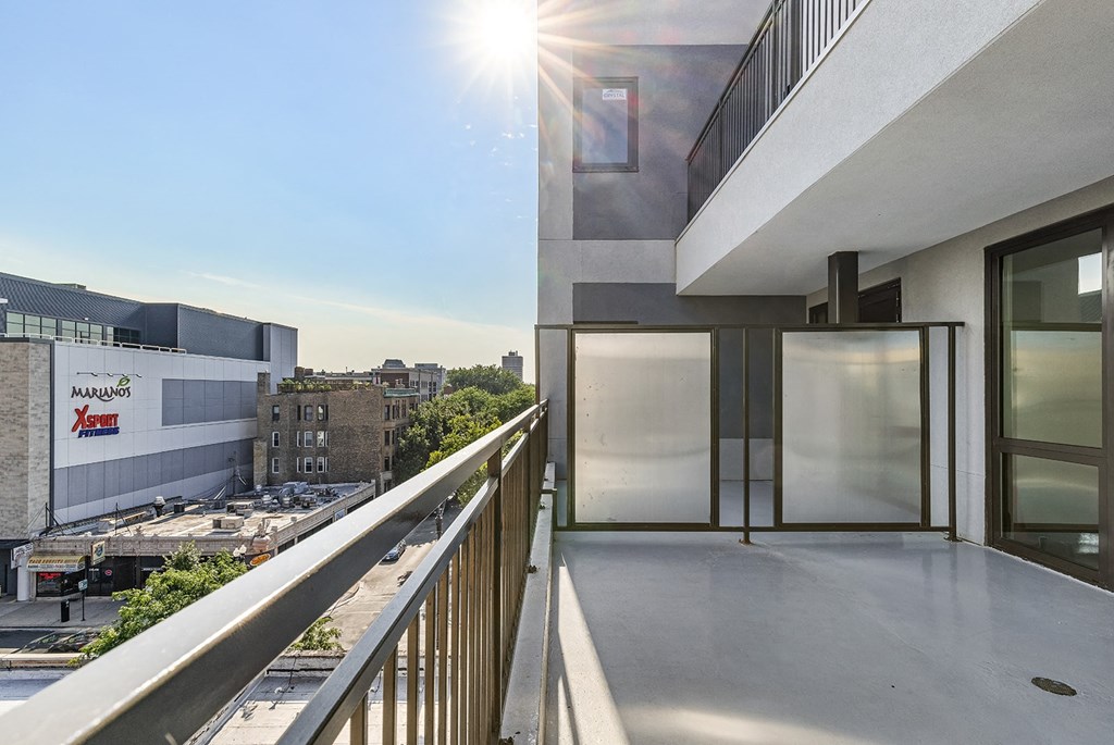 a balcony with a view of a city and a glass door
