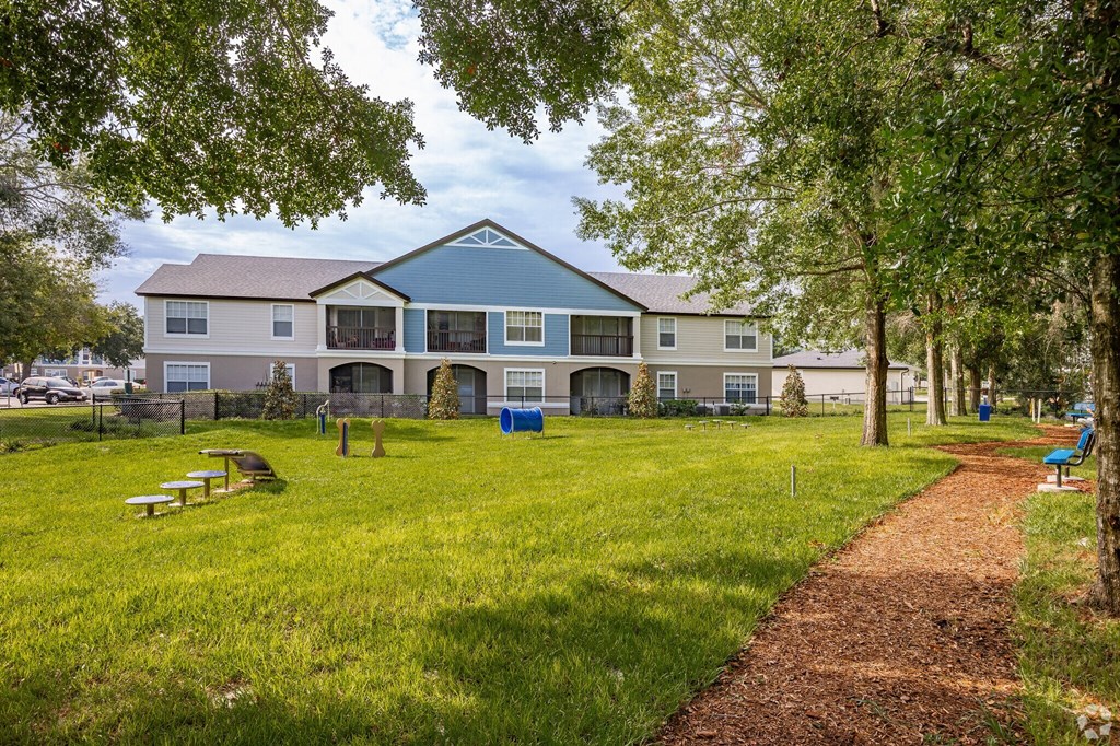 A building with a blue roof is surrounded by a grassy area and trees.
