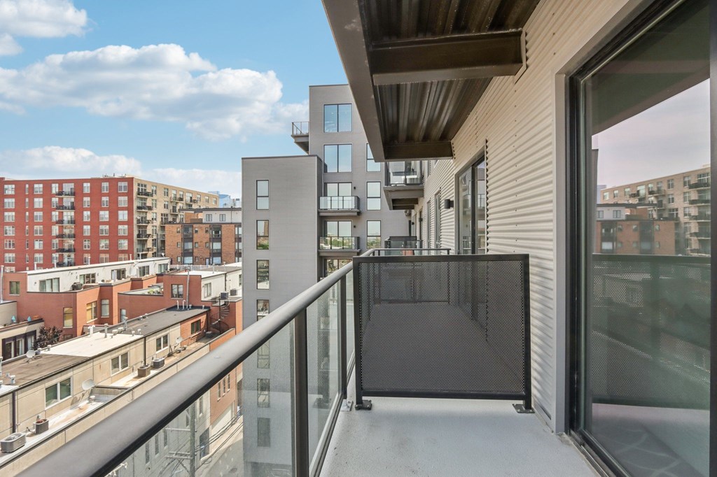 A balcony with a metal railing overlooks a cityscape.