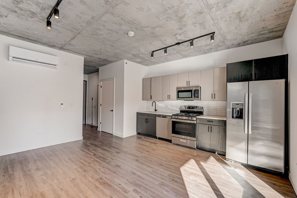 A modern kitchen with stainless steel appliances and wooden floors.