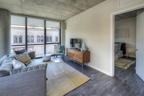 A living room with a grey couch and a wooden cabinet.