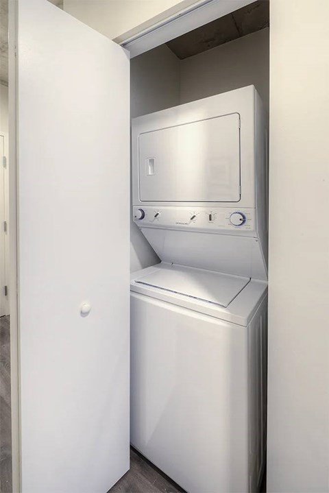A white dryer is in a small space next to a white door.