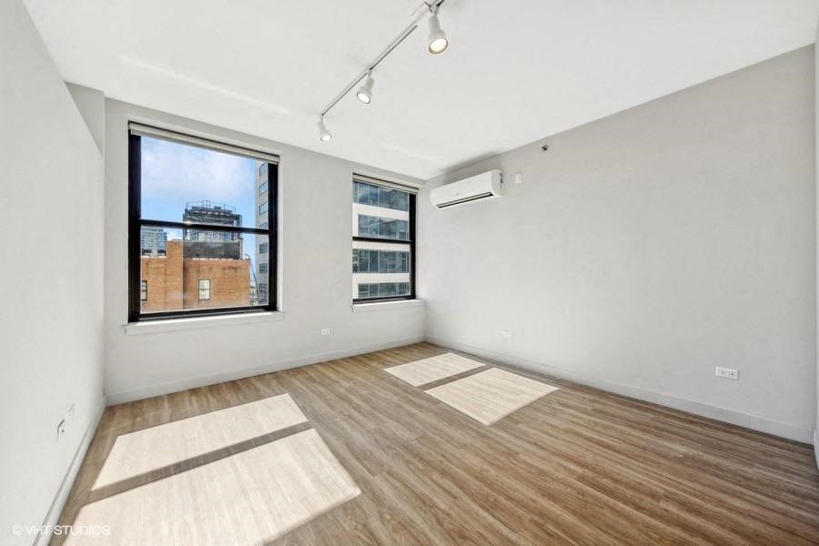 an empty living room with a large window and wood floors